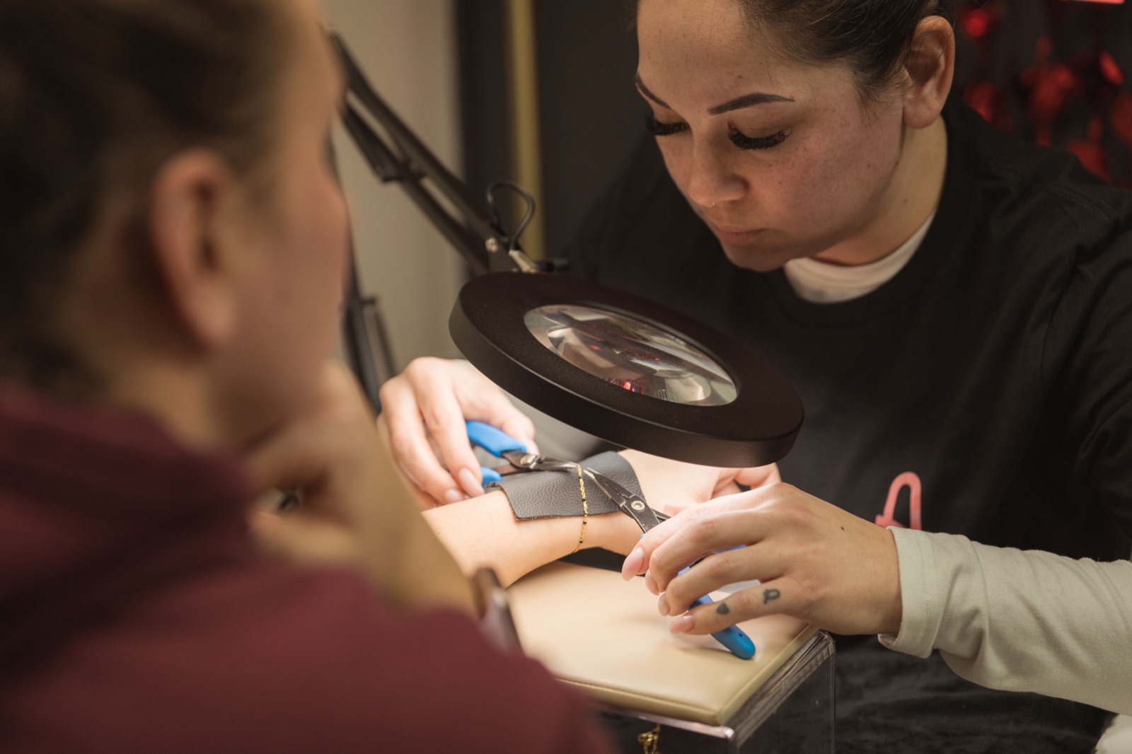 Ashlea fitting a permanent piece with a magnifier and leather wrap